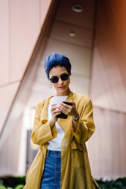 Genç ve çekici Malay Müslüman kadın gündüz elele smartphone
