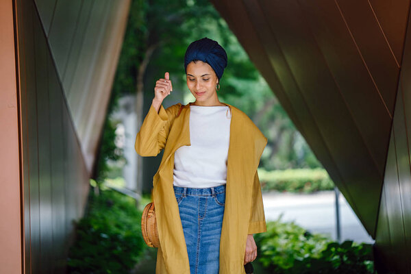 Fashion portrait of a tall, slim, young and attractive Malay Muslim woman wearing fashionable clothing and a turban