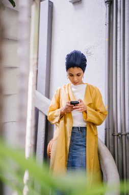 Genç ve çekici Malay Müslüman kadın smartphone elinde tutan 