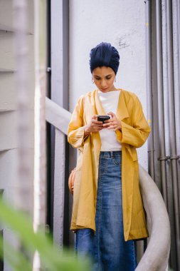 Genç ve çekici Malay Müslüman kadın smartphone elinde tutan 