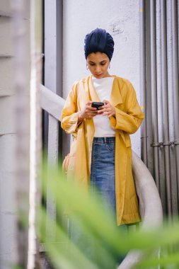 Genç ve çekici Malay Müslüman kadın smartphone elinde tutan 