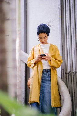 Genç ve çekici Malay Müslüman kadın smartphone elinde tutan 