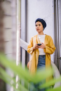 Genç ve çekici Malay Müslüman kadın smartphone elinde tutan 