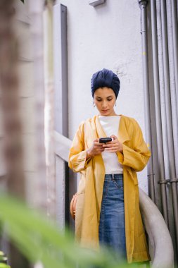 Genç ve çekici Malay Müslüman kadın smartphone elinde tutan 