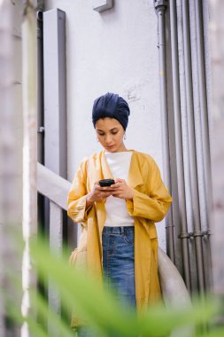 Genç ve çekici Malay Müslüman kadın smartphone elinde tutan 