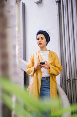 Genç ve çekici Malay Müslüman kadın smartphone elinde tutan 