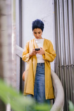 Genç ve çekici Malay Müslüman kadın smartphone elinde tutan 