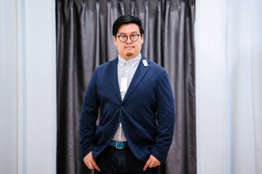 Orta yaşlı bir Çinli giyim ve Konfeksiyon için kendisi için bir hızlı moda mağazasında alışveriş. O giyim giyim mağazası montaj odasında üzerinde çalışıyor.