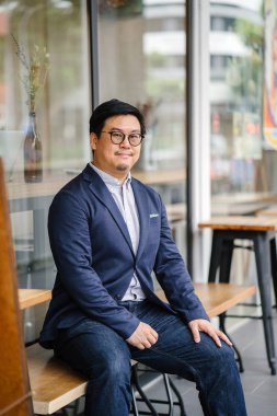 Orta yaşlı Çinli Asyalı portre rahat elbiseli (düğme aşağı oxford gömlek, ceket ve kot pantolon) dostum. O gözlük takıyor ve şık, akıllı, eğitimli ve kendinden emin görünüyor.