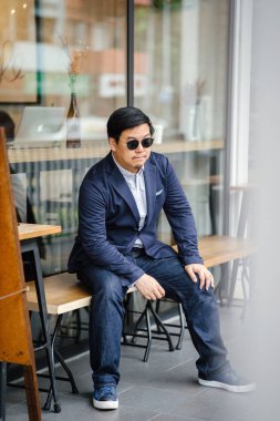 Orta yaşlı Çinli Asyalı portre rahat elbiseli (düğme aşağı oxford gömlek, ceket ve kot pantolon) dostum. O gözlük takıyor ve şık, akıllı, eğitimli ve kendinden emin görünüyor.