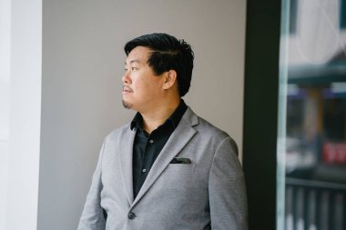 Bir eğitimli ve orta yaşlı Çinli Asyalı (Singapurlu) portresi adam siyah gömlek ve gri takım elbise. 