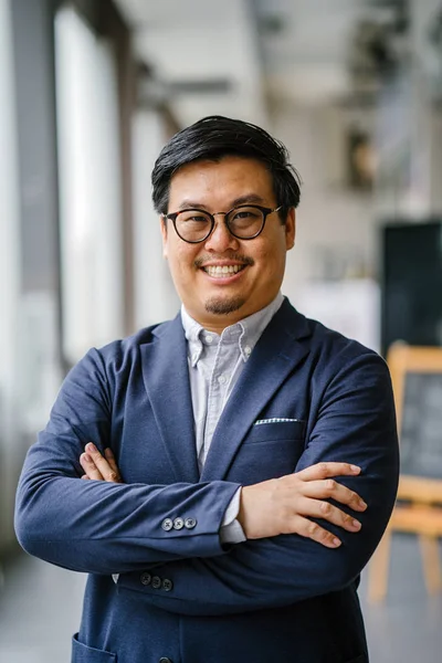 Portrait of a middle-aged Chinese Asian man in a casual suit (button-down oxford shirt, jacket ). He is wearing glasses and looking stylish, smart, educated and confident.