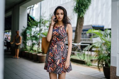 Ayakta ve gün boyunca onun smartphone bir şehirde Asya kentsel bir sokakta konuşurken Genç Hintli Asyalı kadın