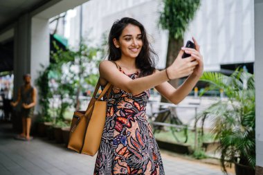 Genç, güzel ve zarif Punjabi Hint Asyalı kadın kendini bir selfie onun smartphone ile yoğun bir cadde üzerinde gün boyunca alır