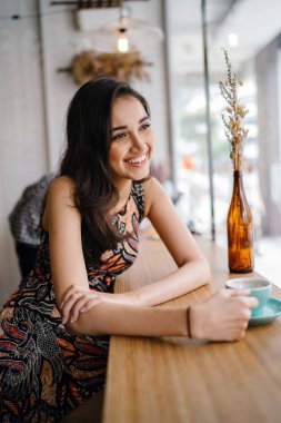 Asya'da hafta sonu seviyor gibi genç ve güzel Hint Asya Singapurlu giysili bir kadına baskı bir kafede oturur.