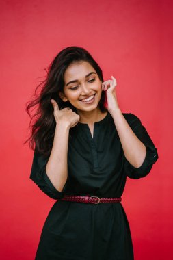 Kızıl stüdyo arka planına karşı güzel, genç ve çekici bir Hintli kadının stüdyo portresi. Zarif giyinmiş.