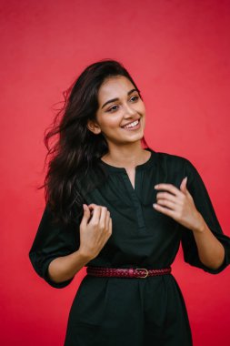 Kızıl stüdyo arka planına karşı güzel, genç ve çekici bir Hintli kadının stüdyo portresi. Zarif giyinmiş.