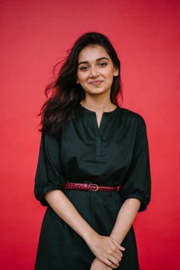 Kızıl stüdyo arka planına karşı güzel, genç ve çekici bir Hintli kadının stüdyo portresi. Zarif giyinmiş.