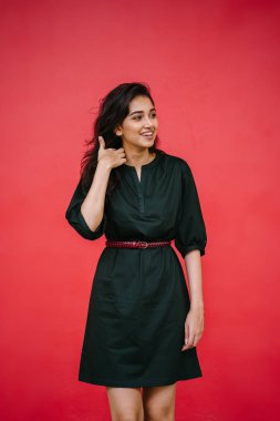 Kızıl stüdyo arka planına karşı güzel, genç ve çekici bir Hintli kadının stüdyo portresi. Zarif giyinmiş.