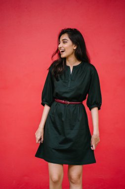 Kızıl stüdyo arka planına karşı güzel, genç ve çekici bir Hintli kadının stüdyo portresi. Zarif giyinmiş.