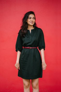 Kızıl stüdyo arka planına karşı güzel, genç ve çekici bir Hintli kadının stüdyo portresi. Zarif giyinmiş.