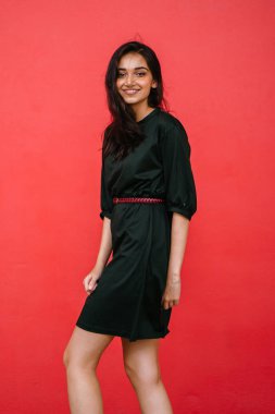 Kızıl stüdyo arka planına karşı güzel, genç ve çekici bir Hintli kadının stüdyo portresi. Zarif giyinmiş.