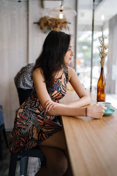 Asya'da hafta sonu seviyor gibi genç ve güzel Hint Asya Singapurlu giysili bir kadına baskı bir kafede oturur.