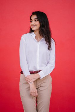 Kızıl stüdyo arka planına karşı güzel, genç ve çekici bir Hintli kadının stüdyo portresi. Zarif giyinmiş.