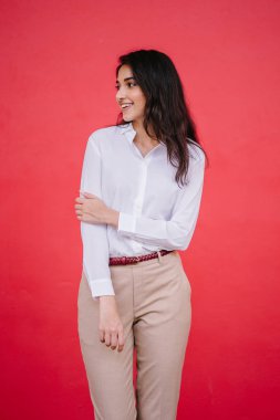 Kızıl stüdyo arka planına karşı güzel, genç ve çekici bir Hintli kadının stüdyo portresi. Zarif giyinmiş.