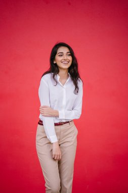 Kızıl stüdyo arka planına karşı güzel, genç ve çekici bir Hintli kadının stüdyo portresi. Zarif giyinmiş.