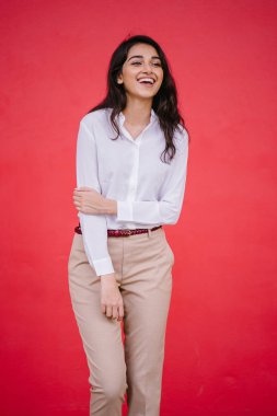 Kızıl stüdyo arka planına karşı güzel, genç ve çekici bir Hintli kadının stüdyo portresi. Zarif giyinmiş.