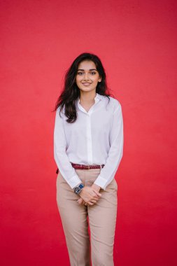 Kızıl stüdyo arka planına karşı güzel, genç ve çekici bir Hintli kadının stüdyo portresi. Zarif giyinmiş.