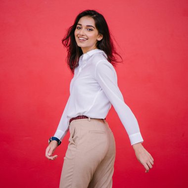 Kızıl stüdyo arka planına karşı güzel, genç ve çekici bir Hintli kadının stüdyo portresi. Zarif giyinmiş.