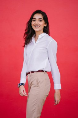 Kızıl stüdyo arka planına karşı güzel, genç ve çekici bir Hintli kadının stüdyo portresi. Zarif giyinmiş.