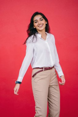 Kızıl stüdyo arka planına karşı güzel, genç ve çekici bir Hintli kadının stüdyo portresi. Zarif giyinmiş.