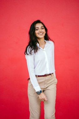 Kızıl stüdyo arka planına karşı güzel, genç ve çekici bir Hintli kadının stüdyo portresi. Zarif giyinmiş.