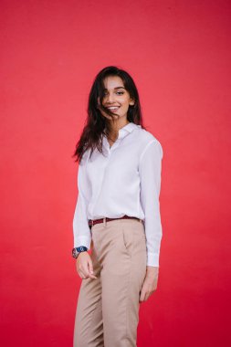 Kızıl stüdyo arka planına karşı güzel, genç ve çekici bir Hintli kadının stüdyo portresi. Zarif giyinmiş.