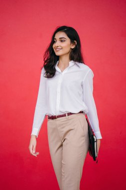 Kızıl stüdyo arka planına karşı güzel, genç ve çekici bir Hintli kadının stüdyo portresi. Zarif giyinmiş.