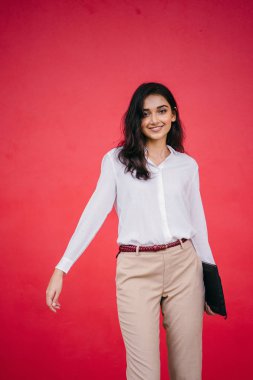 Kızıl stüdyo arka planına karşı güzel, genç ve çekici bir Hintli kadının stüdyo portresi. Zarif giyinmiş.