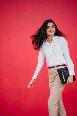 Kızıl stüdyo arka planına karşı güzel, genç ve çekici bir Hintli kadının stüdyo portresi. Zarif giyinmiş.