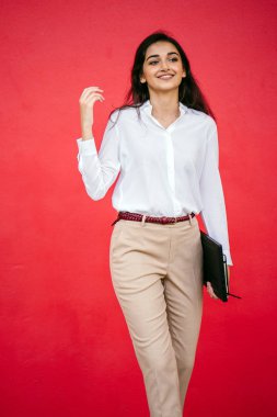 Kızıl stüdyo arka planına karşı güzel, genç ve çekici bir Hintli kadının stüdyo portresi. Zarif giyinmiş.