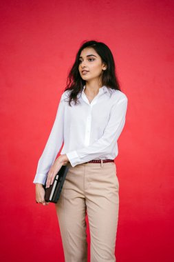 Kızıl stüdyo arka planına karşı güzel, genç ve çekici bir Hintli kadının stüdyo portresi. Zarif giyinmiş.