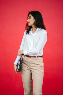 Kızıl stüdyo arka planına karşı güzel, genç ve çekici bir Hintli kadının stüdyo portresi. Zarif giyinmiş.