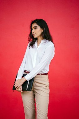 Kızıl stüdyo arka planına karşı güzel, genç ve çekici bir Hintli kadının stüdyo portresi. Zarif giyinmiş.