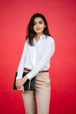 Kızıl stüdyo arka planına karşı güzel, genç ve çekici bir Hintli kadının stüdyo portresi. Zarif giyinmiş.