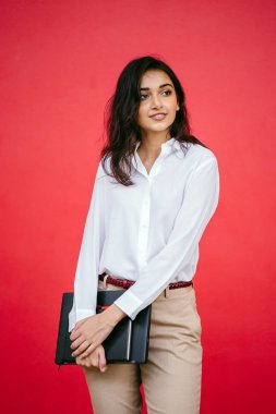 Kızıl stüdyo arka planına karşı güzel, genç ve çekici bir Hintli kadının stüdyo portresi. Zarif giyinmiş.