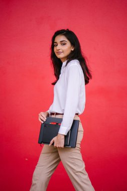 Kızıl stüdyo arka planına karşı güzel, genç ve çekici bir Hintli kadının stüdyo portresi. Zarif giyinmiş.