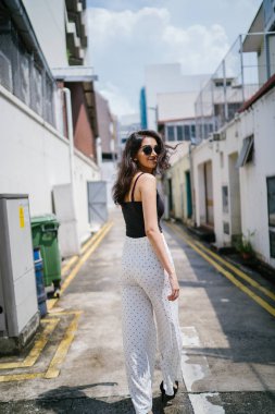 Genç, uzun boylu, ince ve zarif Hint Asyalı kadın rahat bir kıyafet içinde Asya bir sokakta bir sokakta aşağı gün boyunca yürür