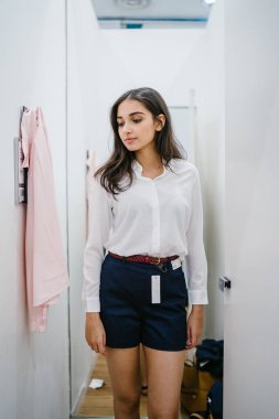 Trying dışarı giyim moda mağaza montaj odasında bir genç, uzun boylu, güzel ve zarif Hint Asyalı kadın portresi.