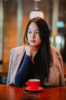 Bir açık havada açık havada oturan ve kırmızı bir çay seti çay sıcak bir fincan zevk genç, çekici, zarif ve güzel Asyalı kadın Portresi. 